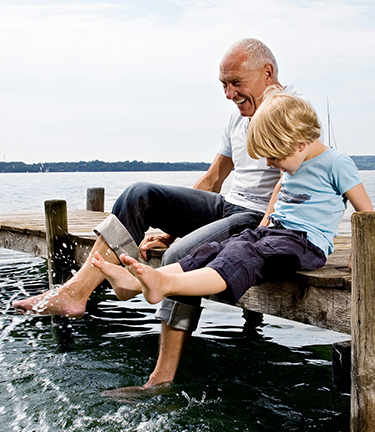 Fully vested employee enjoying retirement with his grandson on a dock with their feet in the water